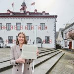 City-Managerin Karin Wessel mit der LoRaWAN-Funkantenne vor dem historischen Rathaus in Linz am Rhein.