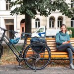 Frau mit Fahrrad sitzt auf einer Bank