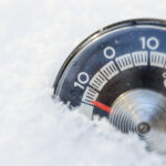 Thermometer steckt im Schnee und zeigt Minusgrade.