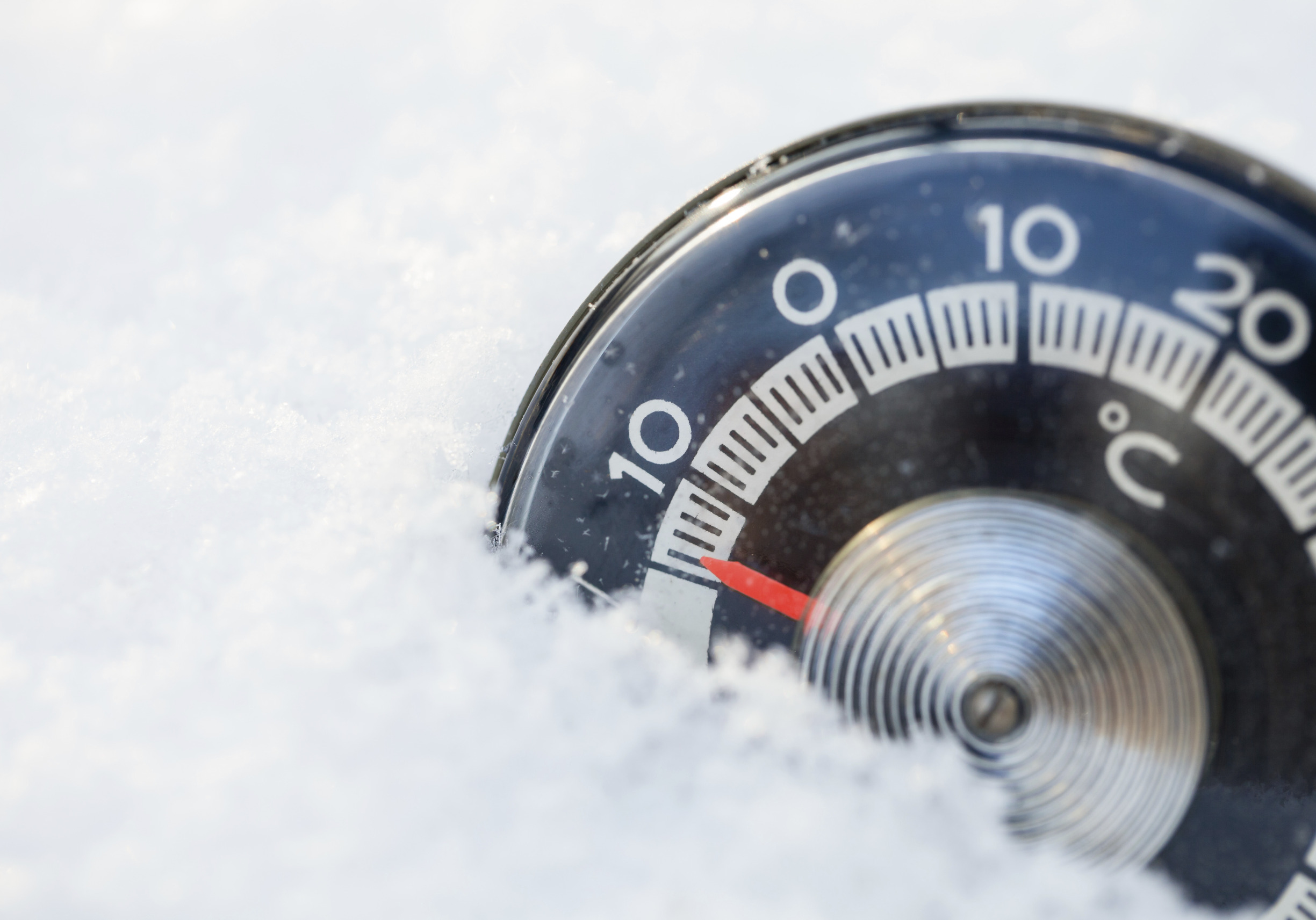 Thermometer steckt im Schnee und zeigt Minusgrade.