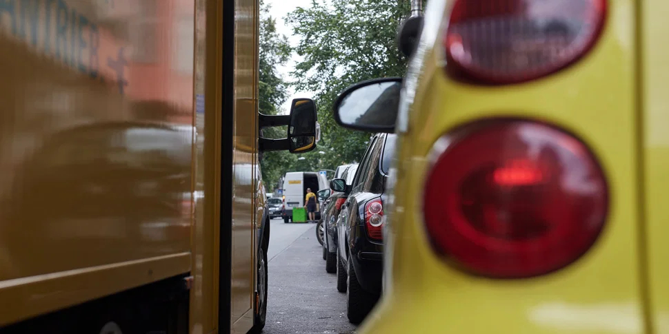 Aufnahme eines zugeparkten Straßenrandes. Der Blick fällt durch den schmalen Abstand zwischen zwei nebeneinander stehenden Autos.