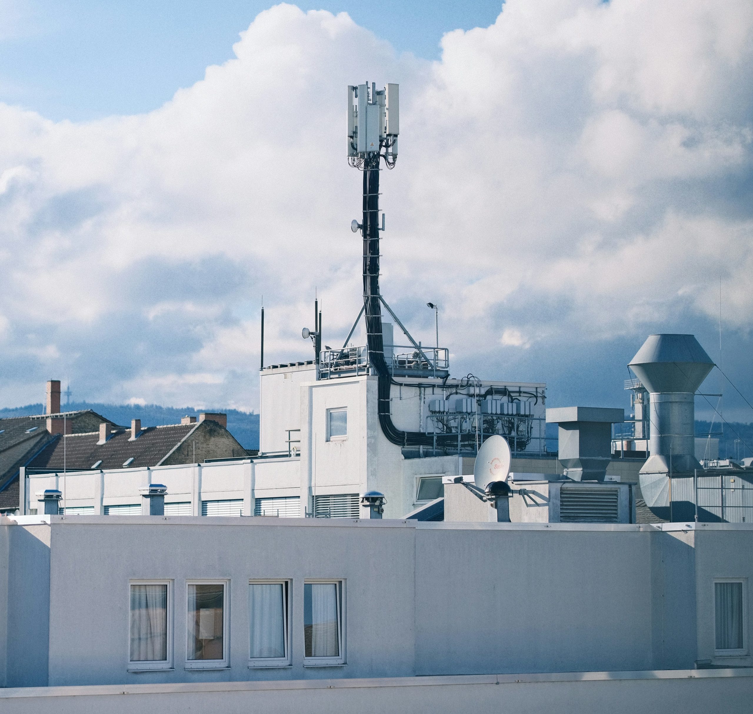 Mobilfunkmast auf einem weißen Gebäude vor Himmel