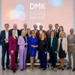 Gruppenfoto der Digitalverantwortlichen der Länder vor einer Projektion mit DMK-Logo.