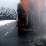 Ein Straufahrzeug, von hinten zu sehen, fährt auf einer Straße, daneben eine schneebedeckte Landschaft.