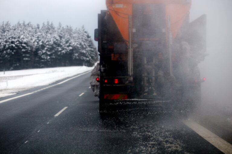 Ein Straufahrzeug, von hinten zu sehen, fährt auf einer Straße, daneben eine schneebedeckte Landschaft.