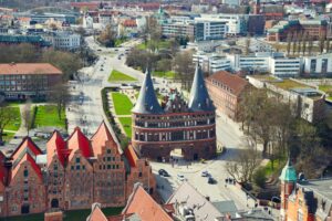 Blick von schräg oben auf den Lübecker Holstentorplatz und Umgebung, im Zentrum das backsteinerne Holstentor mit Kupferdach.