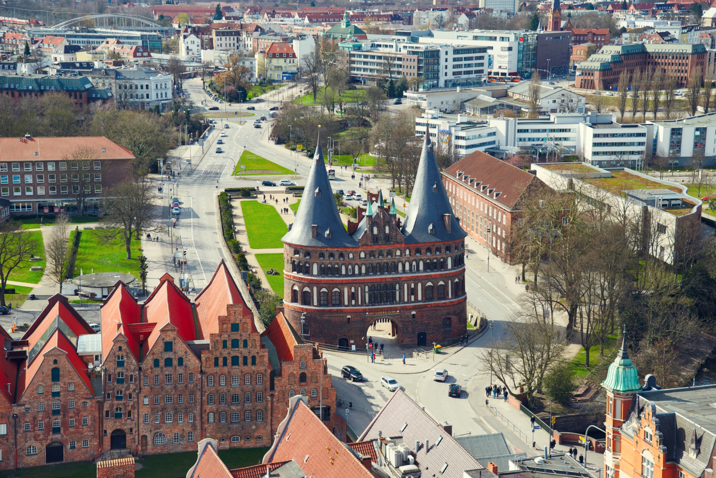 Blick von schräg oben auf den Lübecker Holstentorplatz und Umgebung, im Zentrum das backsteinerne Holstentor mit Kupferdach.