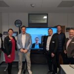 Gruppenfoto das (v.l.) Bürgermeister Tobias Handtke, Miriam Rathmann, Tim Beckmann, Stefan Pahmeier (per Videokonferenz auf einem Bildschirm zugeschaltet), Steffen Matthees, Jan Behrenbruch und Partho Banerjea zeigt.