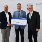 Von links halten Bastian Schäfer von der ekom21, Staatssekretär Martin Rößler und Prof. Dr.-Ing. Jörn Kohlhammer vom Fraunhofer IGD den Förderbescheid des Landes Hessen.