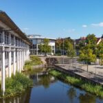 Luftaufnahme des Landratsamts Bayreuth, ein weißes, aus zwei Flügeln bestehendes, circa zweigeschossiges Gebäude an einer Teichanlage.