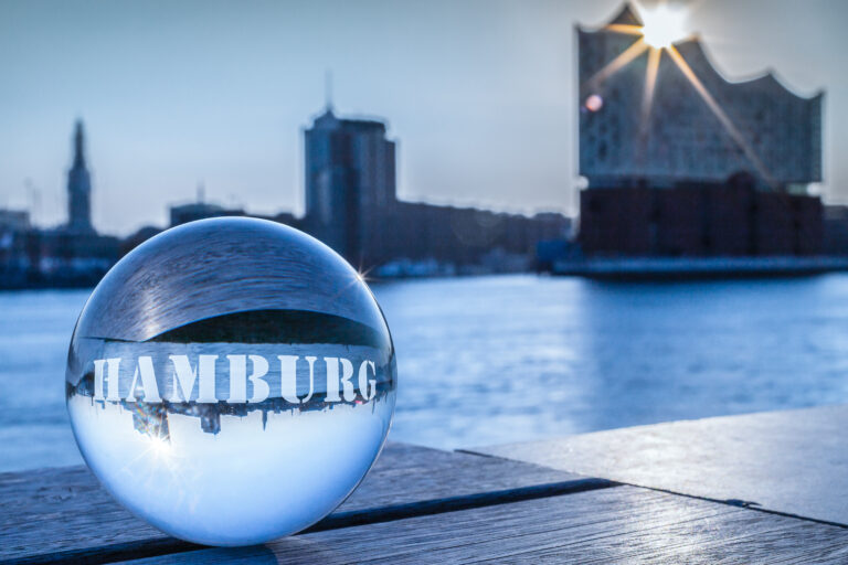 Elbphilharmonie spiegelt sich in einer Glaskugel mit dem Wort Hamburg