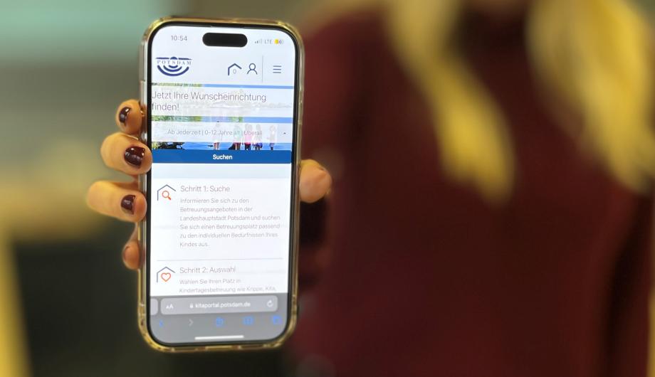 Hand mit Handy auf dem Potsdams Kitaportal läuft