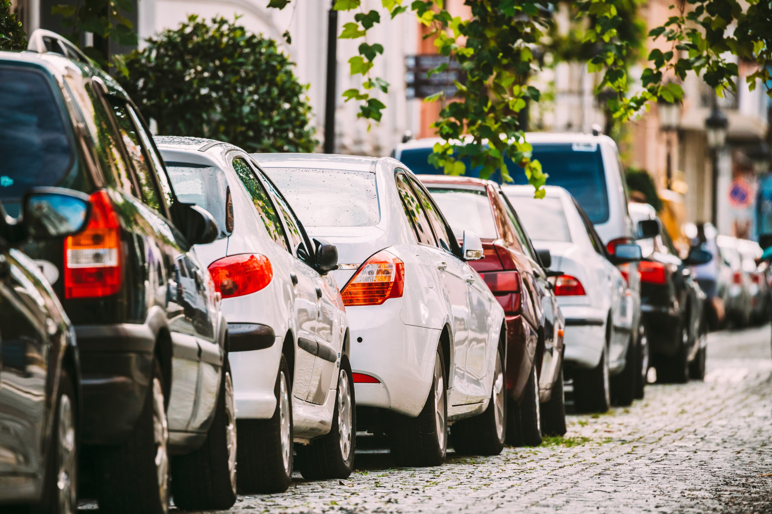 Reihe von Autos, die in einer Straße parkt,, der Bildhintergrund ist unscharf.