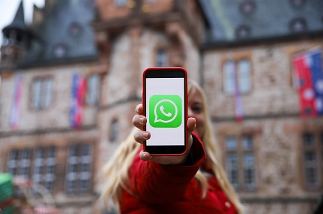 Eine Frau hält eine Mobiltelefon, dass das Whatsapp Symbol zeigt.