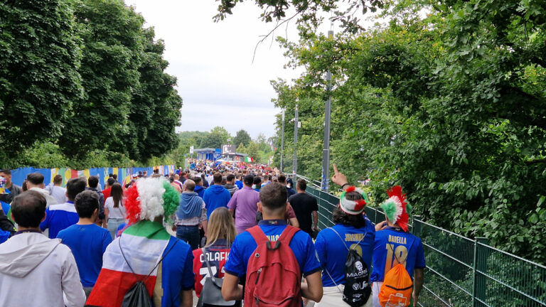 Fans strömen in ein Fußballstadion.