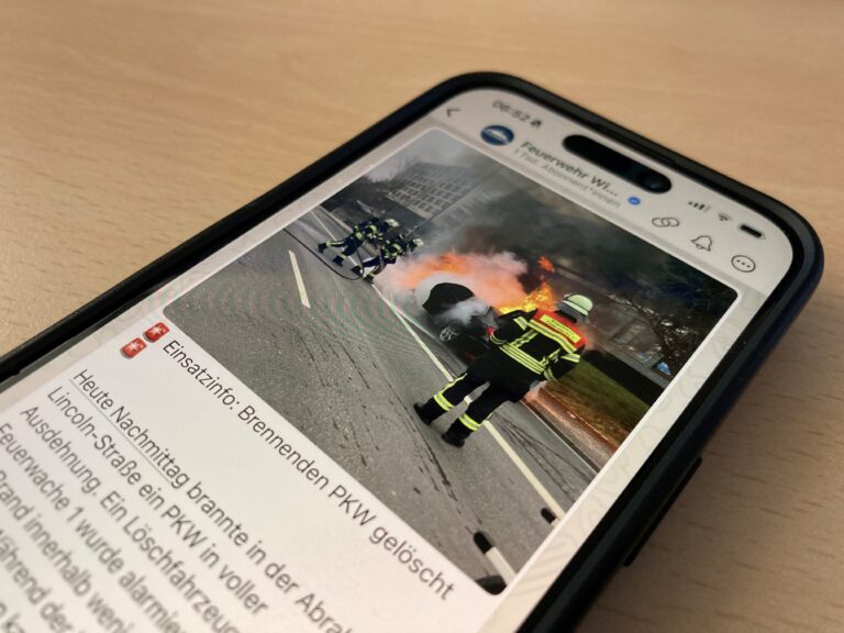 Auf einem Smartphone ist ein Beitrag auf dem WhatsApp-Kanal der Feuerwehr Wiesbaden zu sehen