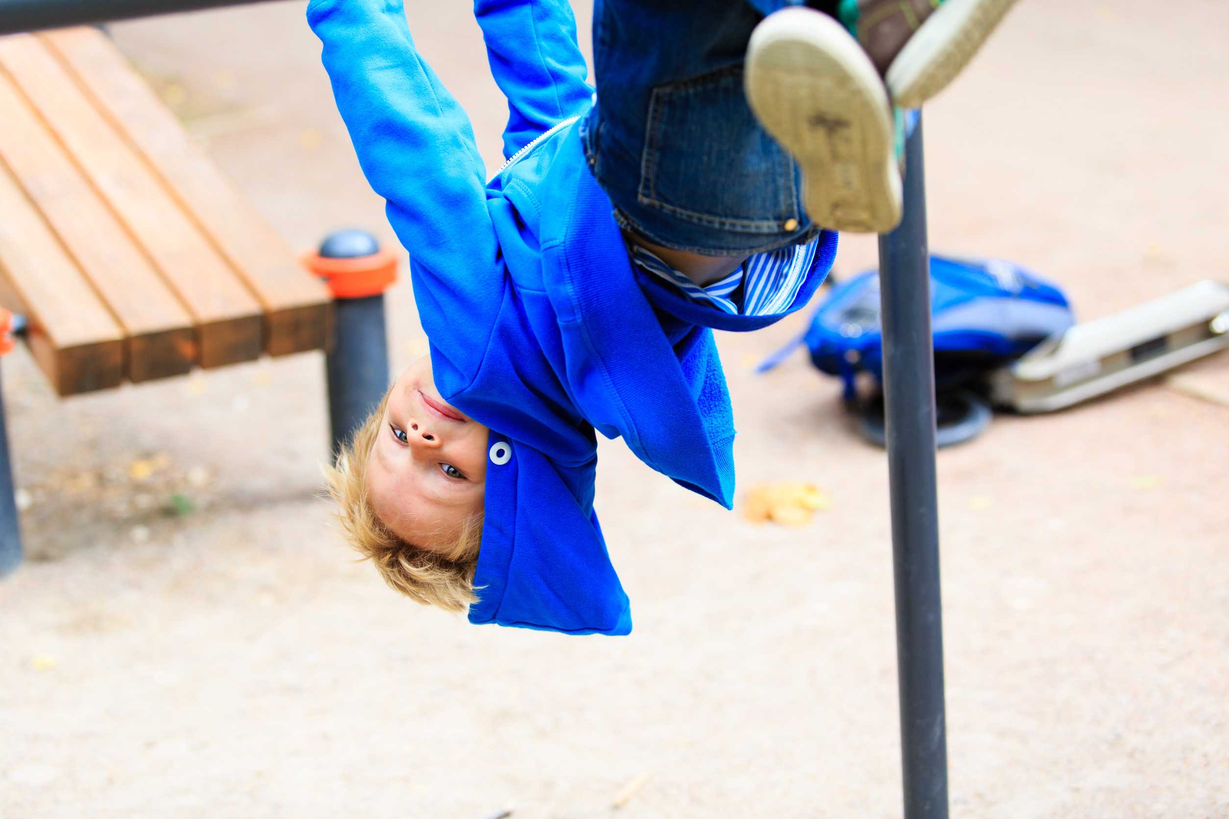 Kleiner Junge turnt an einem Spielplatz-Gerät.