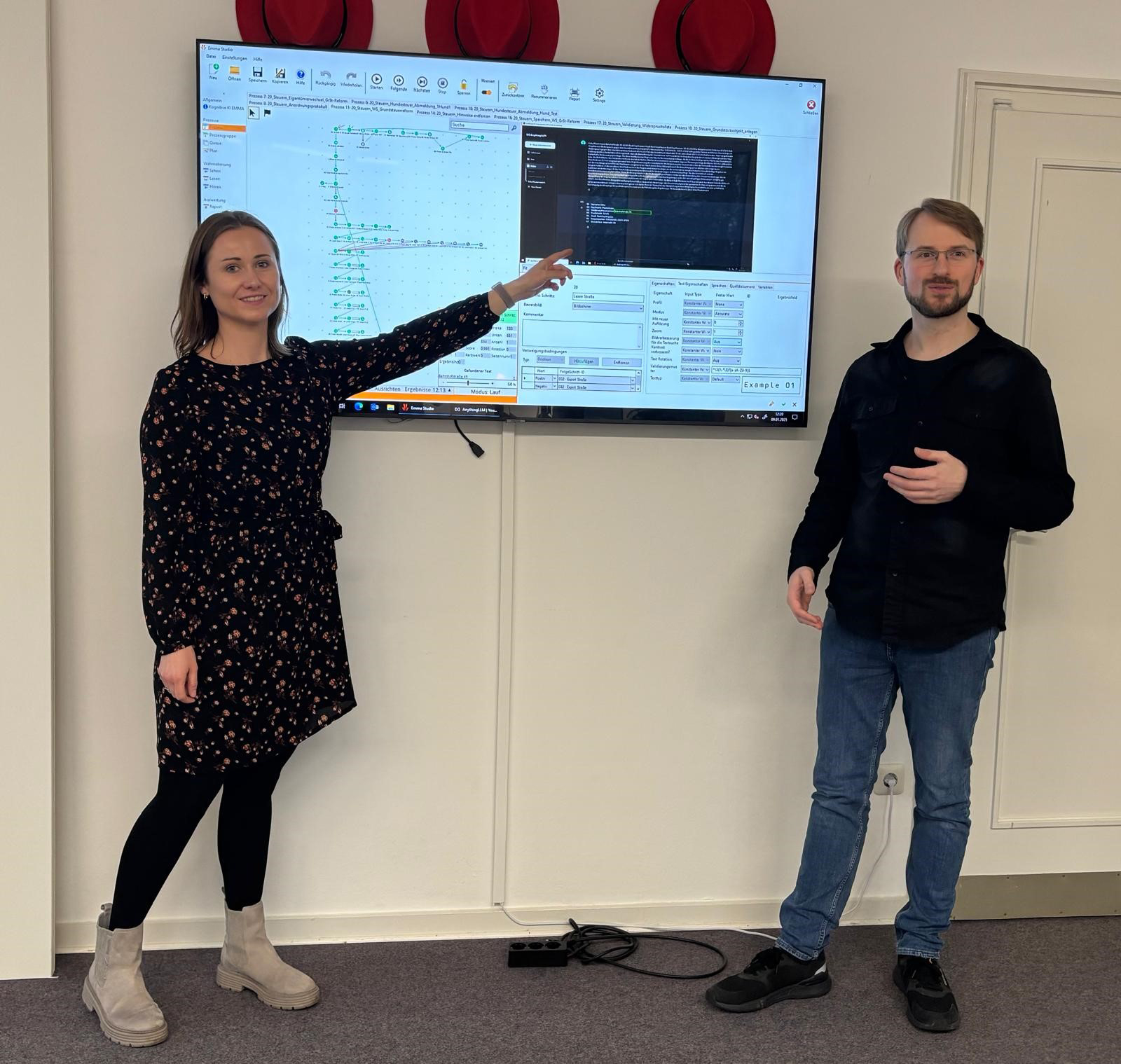 Julia Kleinert vom Team Organisation der Stadt Bad Oeynhausen und Patrick Höwener vom Team Steuern stehen vor einem an der Wand befestigten Whiteboard und erklären darauf den neuen Prozess mit EMMA.