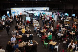 Blick auf eine Halle, in der Menschen an Tischen sitzen.